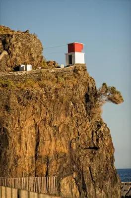 a lighthouse on the side of a rocky cliff at Hostel Casal São João in Ribeira Brava