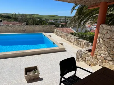a swimming pool with a chair next to a house at Villa Boa Vista Sul - Terra da Eira - Raposeira in Vila do Bispo