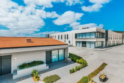 an exterior view of a white building with a red roof at Vila Baleira Village in Porto Santo