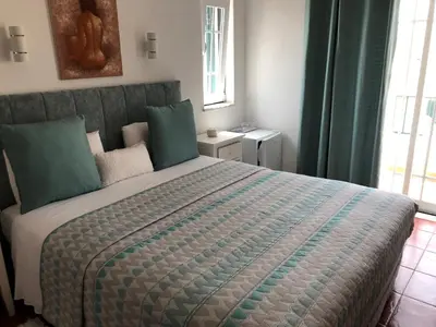 a bedroom with a large bed with green pillows at Casa GiGi in Sagres