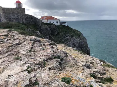 a lighthouse on the edge of a cliff near the ocean at Casa GiGi in Sagres