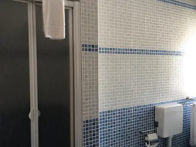 a blue tiled bathroom with a shower and a toilet at Casa GiGi in Sagres