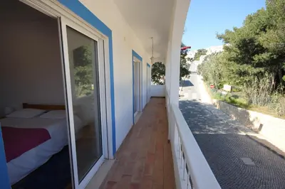 a balcony with a bed and a view of a street at T3 Casa dos Arcos by Seewest in Salema