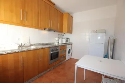 a kitchen with wooden cabinets and a white refrigerator at T3 Casa dos Arcos by Seewest in Salema