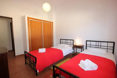 two beds with red sheets in a room at T2 Casa dos Arcos by Seewest in Salema