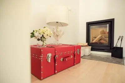 a red suitcase with flowers in a room with a fireplace at Vigia da Areia in São Lourenço