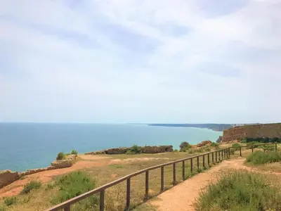 a dirt road with a fence next to the ocean at Casas da Vila in Luz