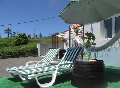 two chairs and an umbrella on a patio at Casa Formiga in Fajã da Ovelha