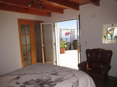 a bedroom with a bed and a chair and a sliding glass door at Casa Formiga in Fajã da Ovelha