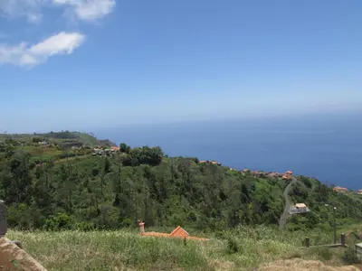 a green hill with houses on top of it at Casa Formiga in Fajã da Ovelha
