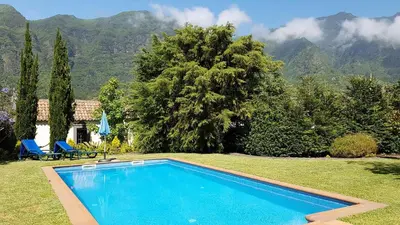 a swimming pool in a yard with mountains in the background at Casa da Portada in São Vicente