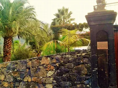 a stone wall with palm trees in the background at Casa da Portada in São Vicente