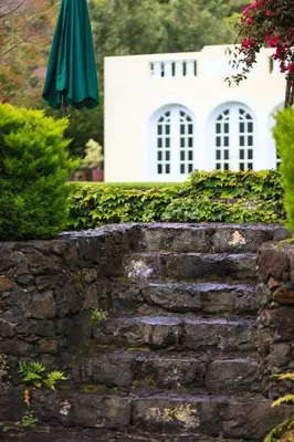 a stone retaining wall with an umbrella in front of a house at Casa da Portada in São Vicente