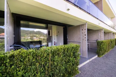 a building with large sliding glass doors and bushes at Casa do Manuel in Santana