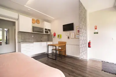 a bedroom with a bed and a table and a kitchen at Casa do Manuel in Santana