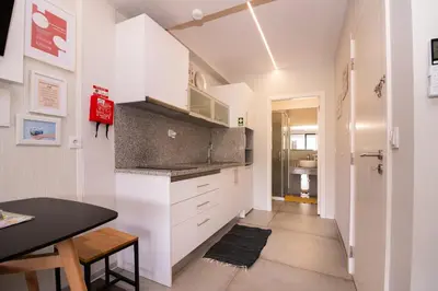 a kitchen with white cabinets and a black table at Casa do Manuel in Santana