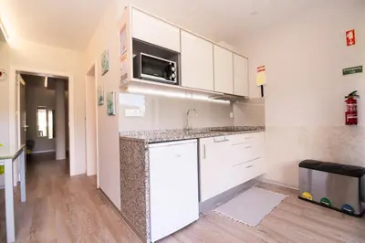 a kitchen with white cabinets and a sink and a microwave at Casa do Manuel in Santana