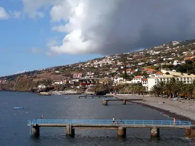 a pier in the water near a beach with a town at Morena house in Santa Cruz
