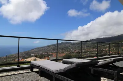a bench on a balcony with a view of a mountain at A&M House in Arco da Calheta