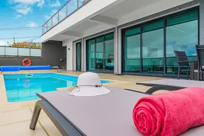 a house with a pool and a pink towel on a table at A&M House in Arco da Calheta