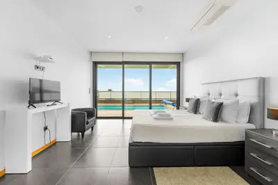a bedroom with a bed and a television and a pool at A&M House in Arco da Calheta