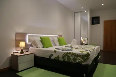 a bedroom with a large bed with green pillows at A&M House in Arco da Calheta