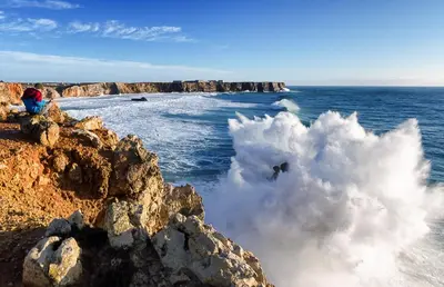 a person jumping off of a wave in the ocean at Mareta Beach House - Boutique Residence in Sagres