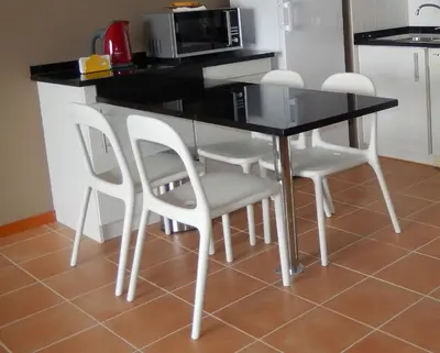 a kitchen table with white chairs and a microwave at Apartamento Bela Vista in Porto Santo