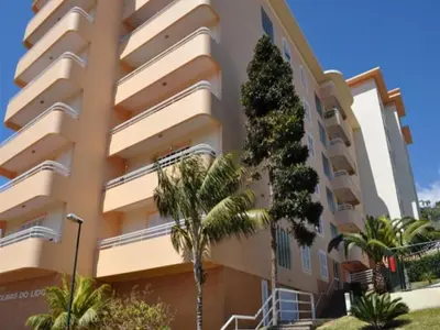 a large apartment building with palm trees in front of it at Colinas do Lido III by Rentallido in Funchal