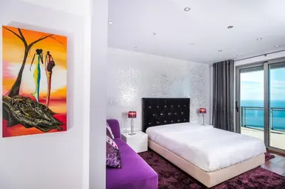 a bedroom with a white bed and a purple couch at Villa São Lourenço in Fajã da Ovelha