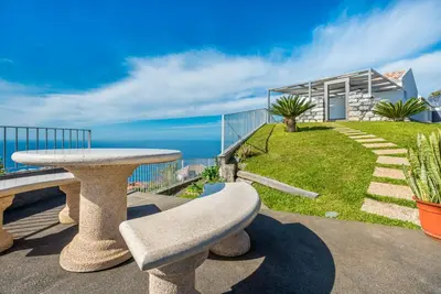a patio with a table and a view of the ocean at Villa São Lourenço in Fajã da Ovelha
