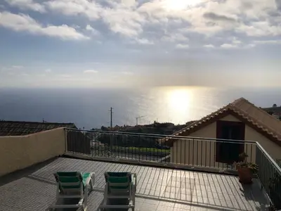 a balcony with two chairs and a view of the ocean at Casa da Rainha in Calheta