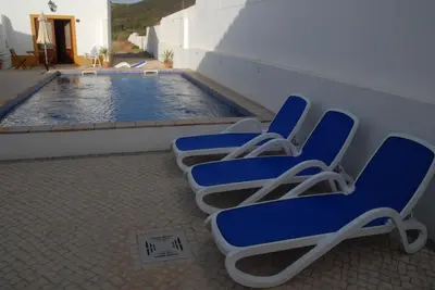 a row of chairs sitting next to a swimming pool at Carrapateiramar Guest House in Carrapateira
