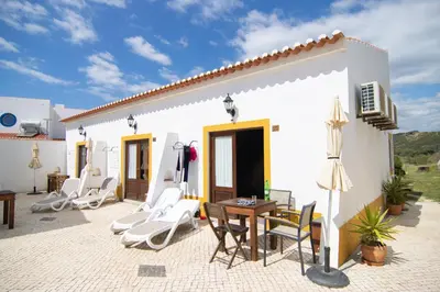 a patio of a house with chairs and a table at Carrapateiramar Guest House in Carrapateira