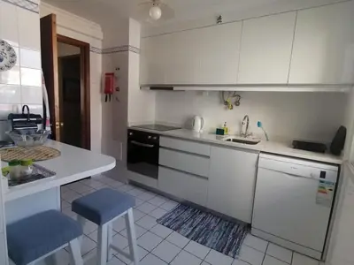 a kitchen with white cabinets and a blue stool at Ladeira Centro in Funchal