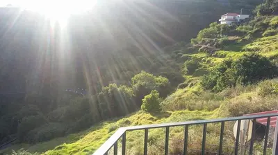 a sun shining on a grassy hill with a house on it at Maison Zita in Venda do Atalhinho