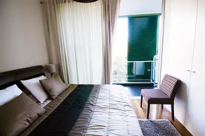 a bedroom with a bed and a chair and a window at Quinta da Nogueira in Funchal