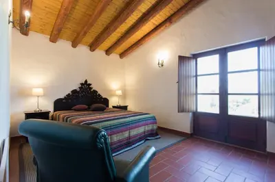 a bedroom with a bed and a chair and a window at Casas da Capela do Monte, Country Houses in Lagos