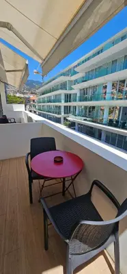 a red table and chairs on a balcony with a building at Canavial Terrace@Heart of Funchal in Funchal