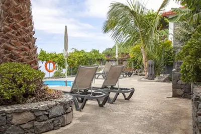 a group of chairs sitting next to a pool at Quinta Golfinho in Arco da Calheta