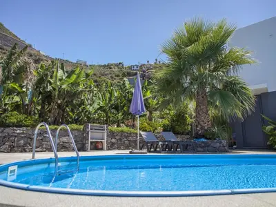 a swimming pool in a resort with palm trees at Quinta Golfinho in Arco da Calheta