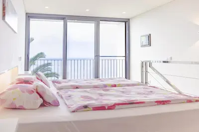 a white bedroom with two beds and a window at Quinta Golfinho in Arco da Calheta
