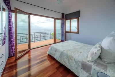 a bedroom with a bed and a balcony at Casa Falésia in Caniço