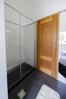 a room with a shower and a wooden door at Casa Falésia in Caniço