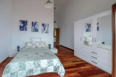 a white bedroom with a bed and a dresser at Casa Falésia in Caniço