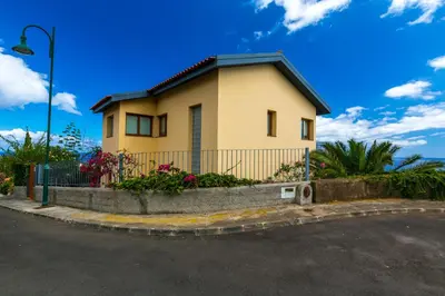 a yellow house with a fence and flowers at Casa Falésia in Caniço