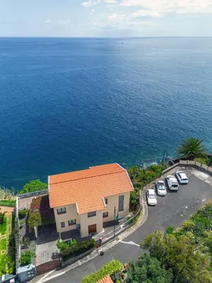 an aerial view of a building with cars parked next to the ocean at Casa Falésia in Caniço