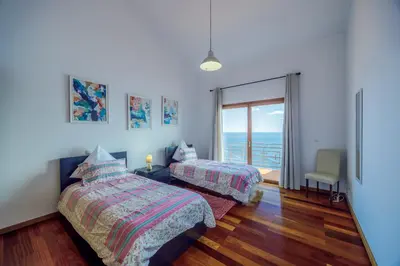 a bedroom with two beds and a view of the ocean at Casa Falésia in Caniço