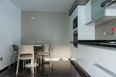a kitchen with white cabinets and a table and chairs at Vilas Mediterrâneo in Santa Cruz