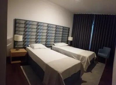 a hotel room with two beds and a chair at Vilas Mediterrâneo in Santa Cruz